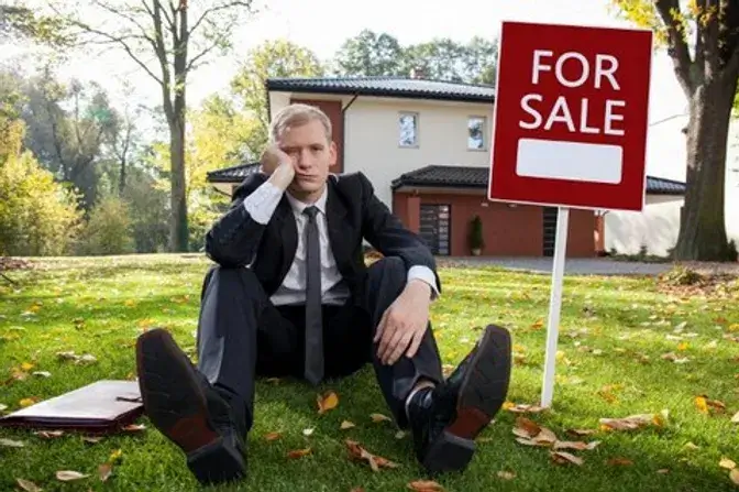 the stressed homeowner sitting in front of house that is in foreclousure