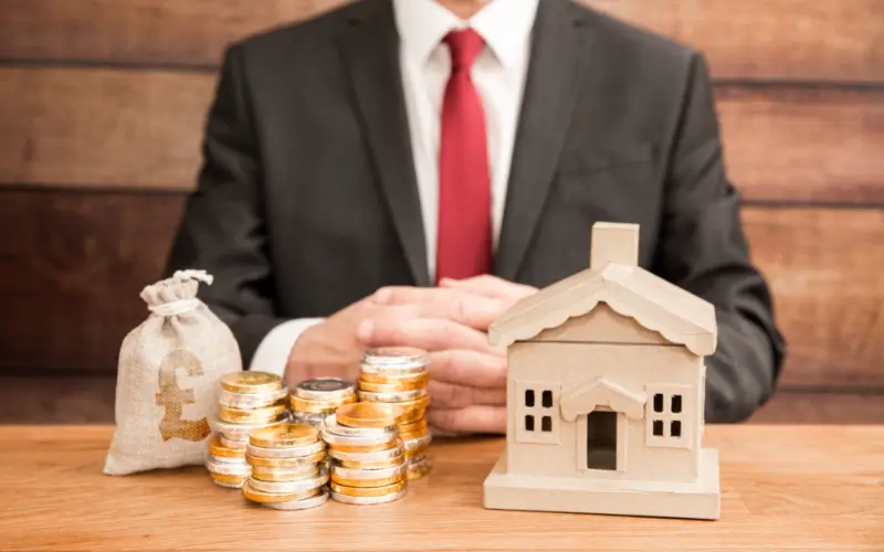 Businessman with a model house, coins, and a money bag, symbolizing home cash buyers and real estate transactions.