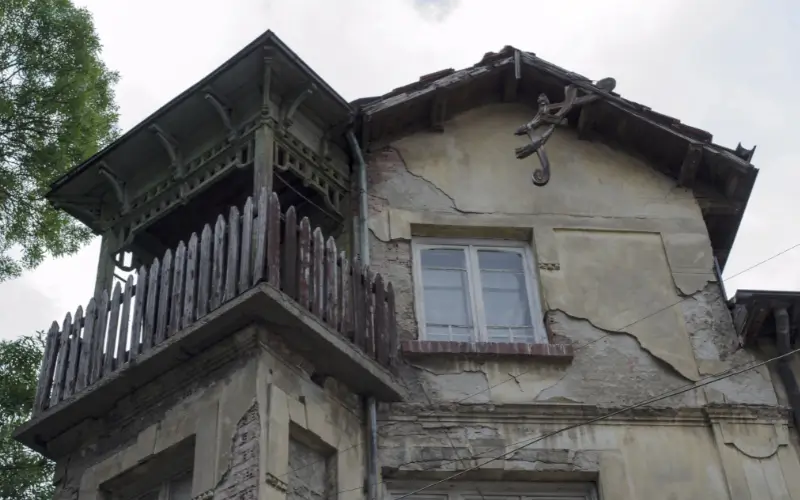 Old house with cracked walls and broken balcony, representing selling a house without repairs.